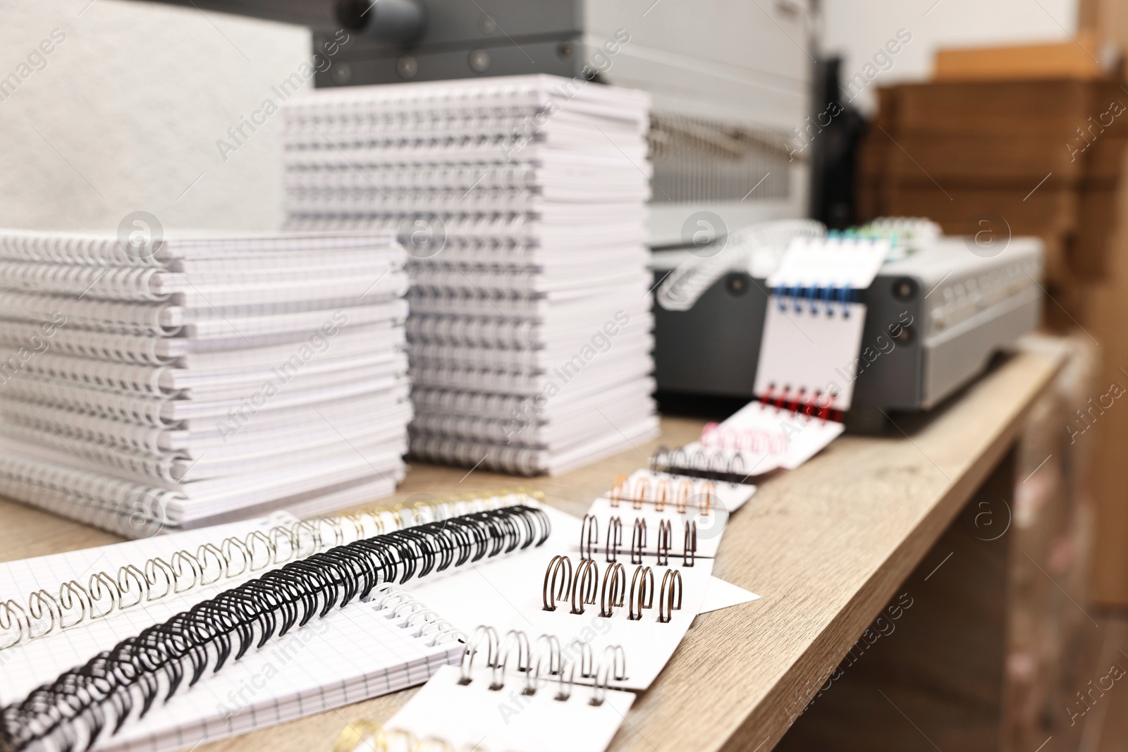 Photo of Stacks of notebooks and double loop wire binding spines on wooden table indoors, closeup