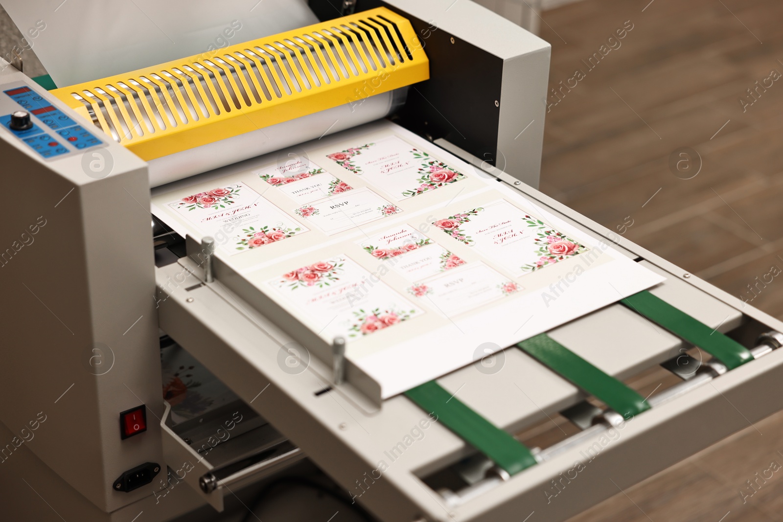 Photo of Modern roll laminator and paper sheet with invitation cards indoors, closeup. Printing house