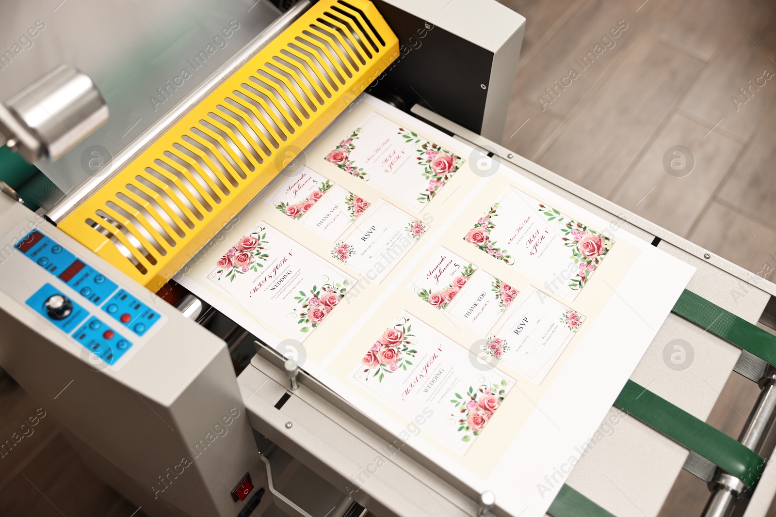 Photo of Modern roll laminator and paper sheet with invitation cards indoors, closeup. Printing house