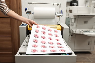 Photo of Woman with printed flower stickers indoors, closeup. Printing house