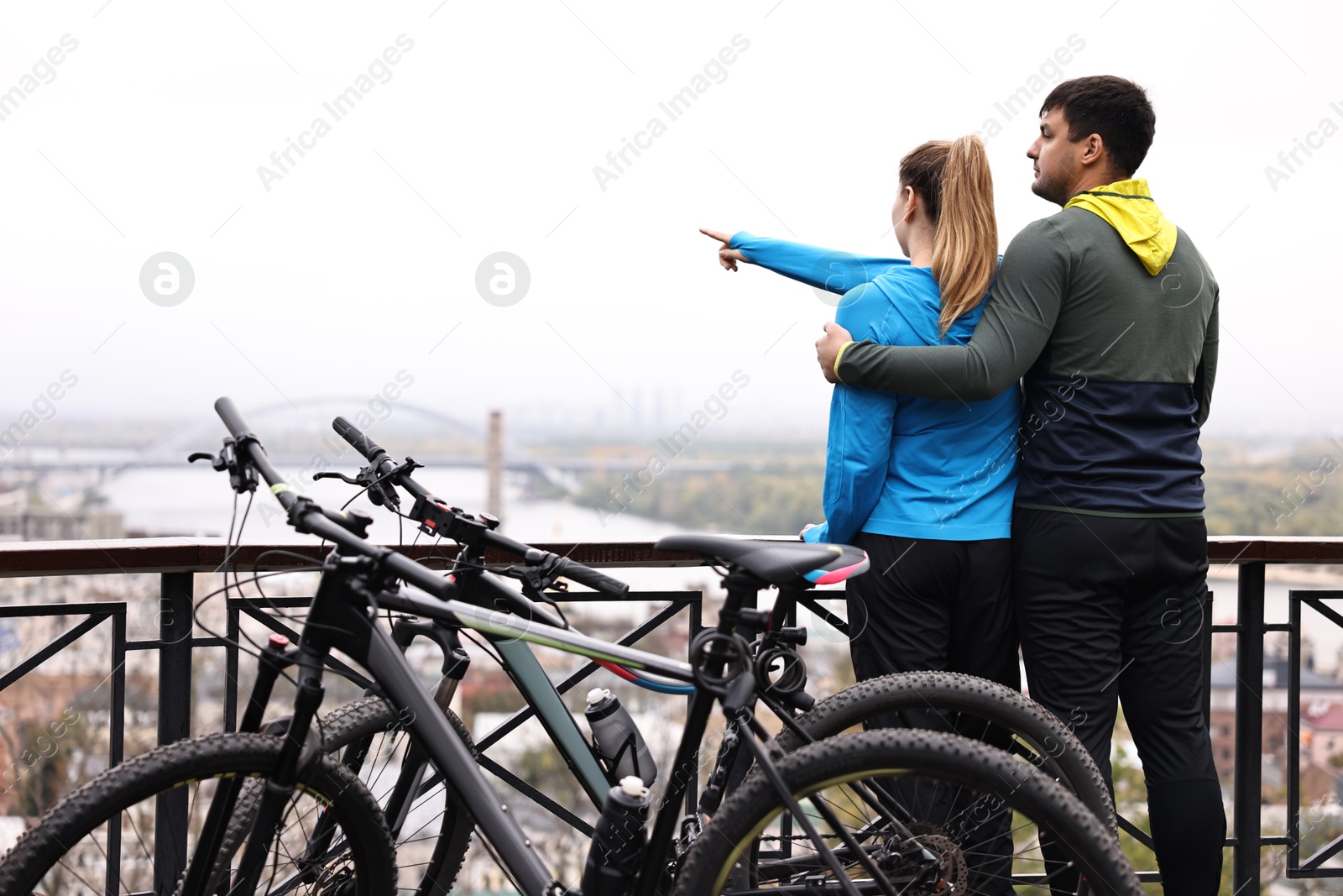 Photo of Beautiful happy couple with bicycles spending time together outdoors, back view