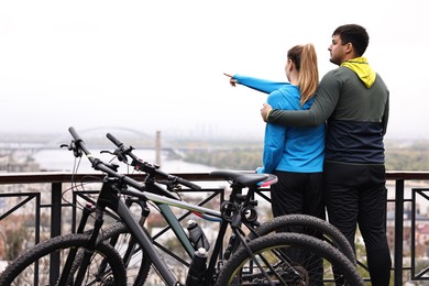 Photo of Beautiful happy couple with bicycles spending time together outdoors, back view