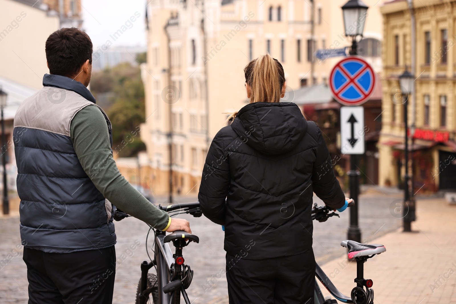 Photo of Couple with bicycles spending time together outdoors, back view