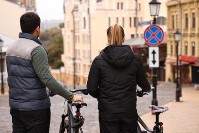 Couple with bicycles spending time together outdoors, back view