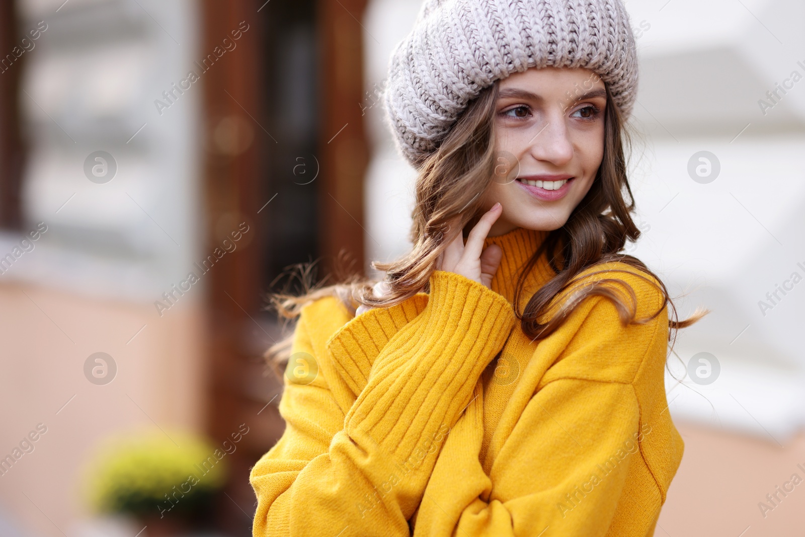 Photo of Beautiful young woman in warm sweater and hat outdoors. Autumn mood