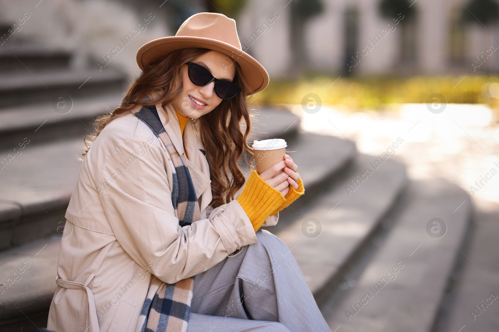 Photo of Charming young woman with cup of coffee on city street. Autumn season