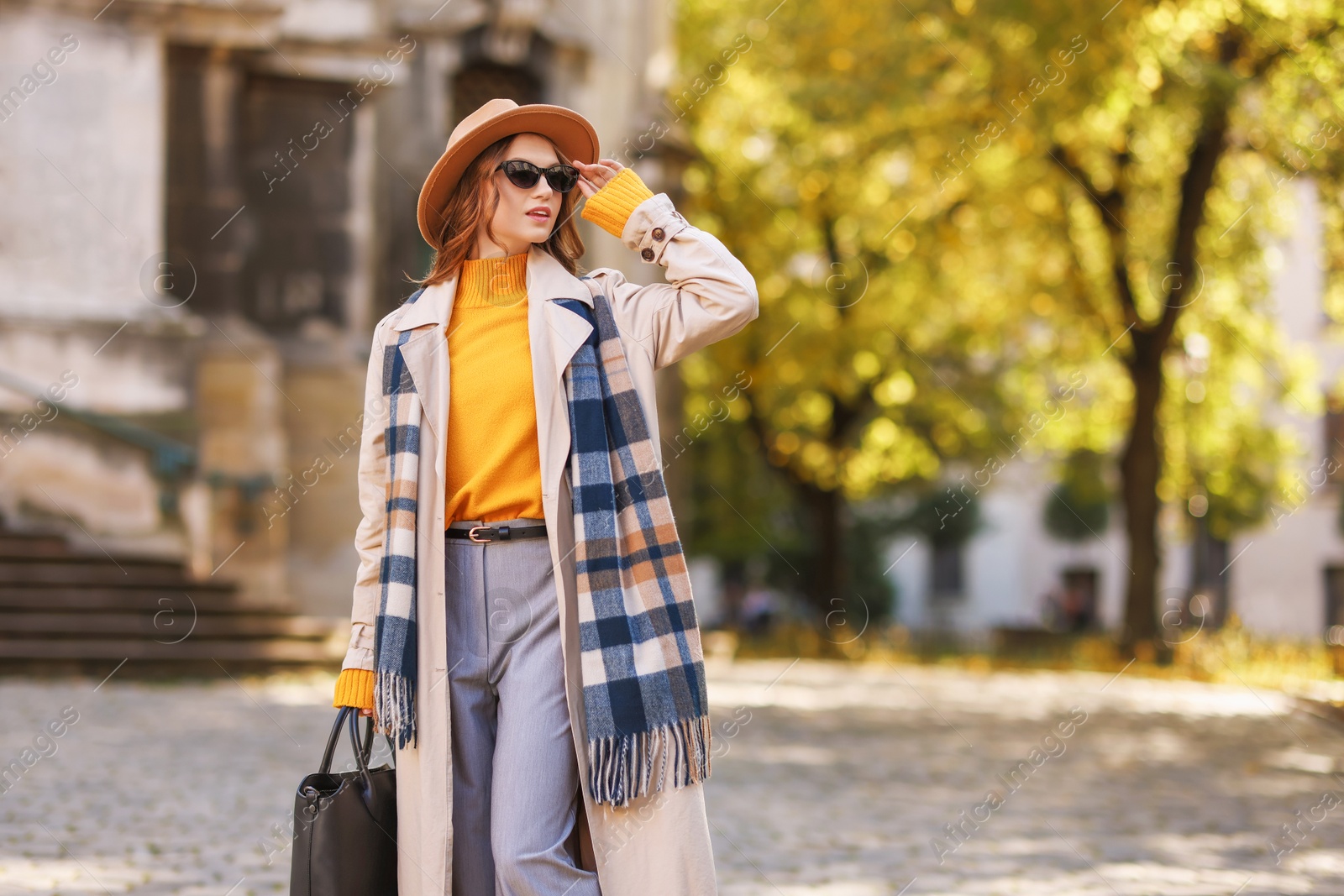 Photo of Charming young woman in stylish outfit on city street, space for text. Autumn season