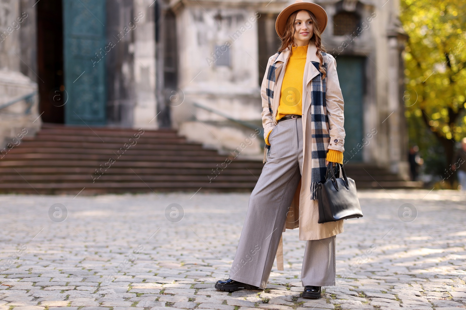 Photo of Charming young woman in stylish outfit on city street, space for text. Autumn season