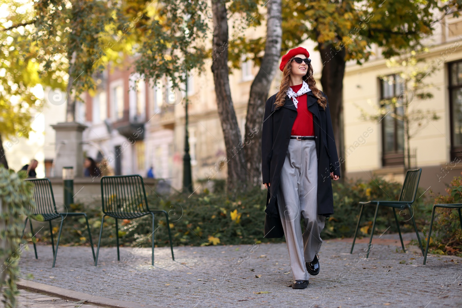 Photo of Charming young woman in stylish outfit on city street, space for text. Autumn season