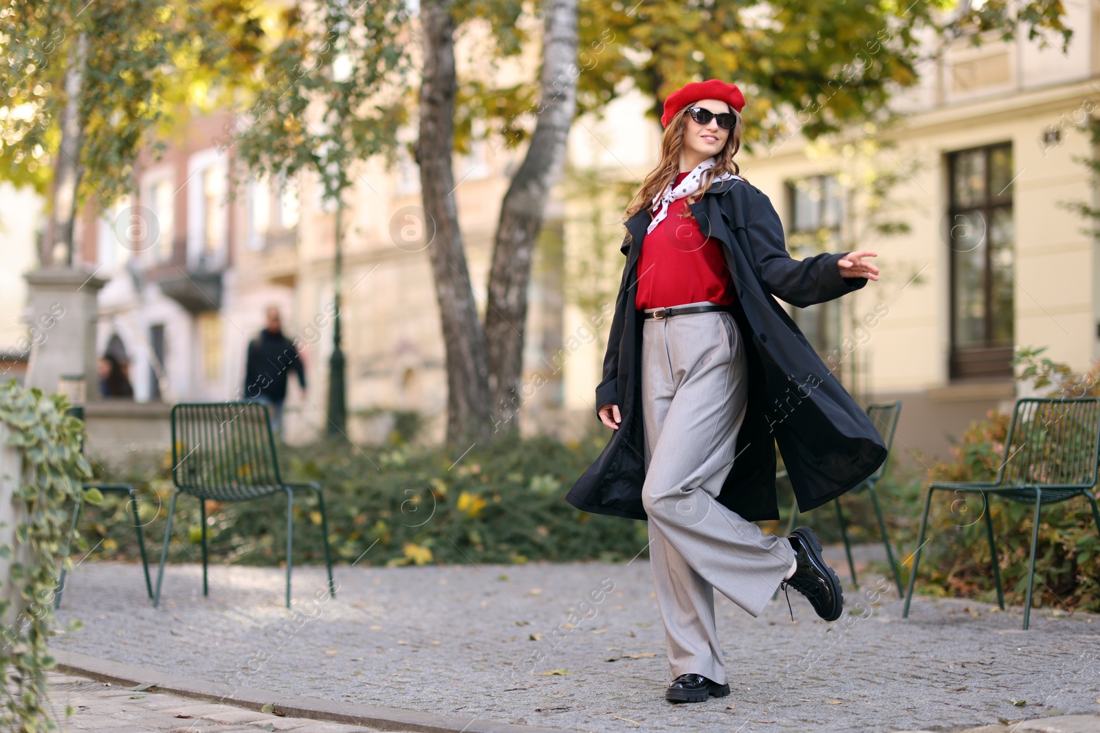 Photo of Charming young woman in stylish outfit on city street, space for text. Autumn season