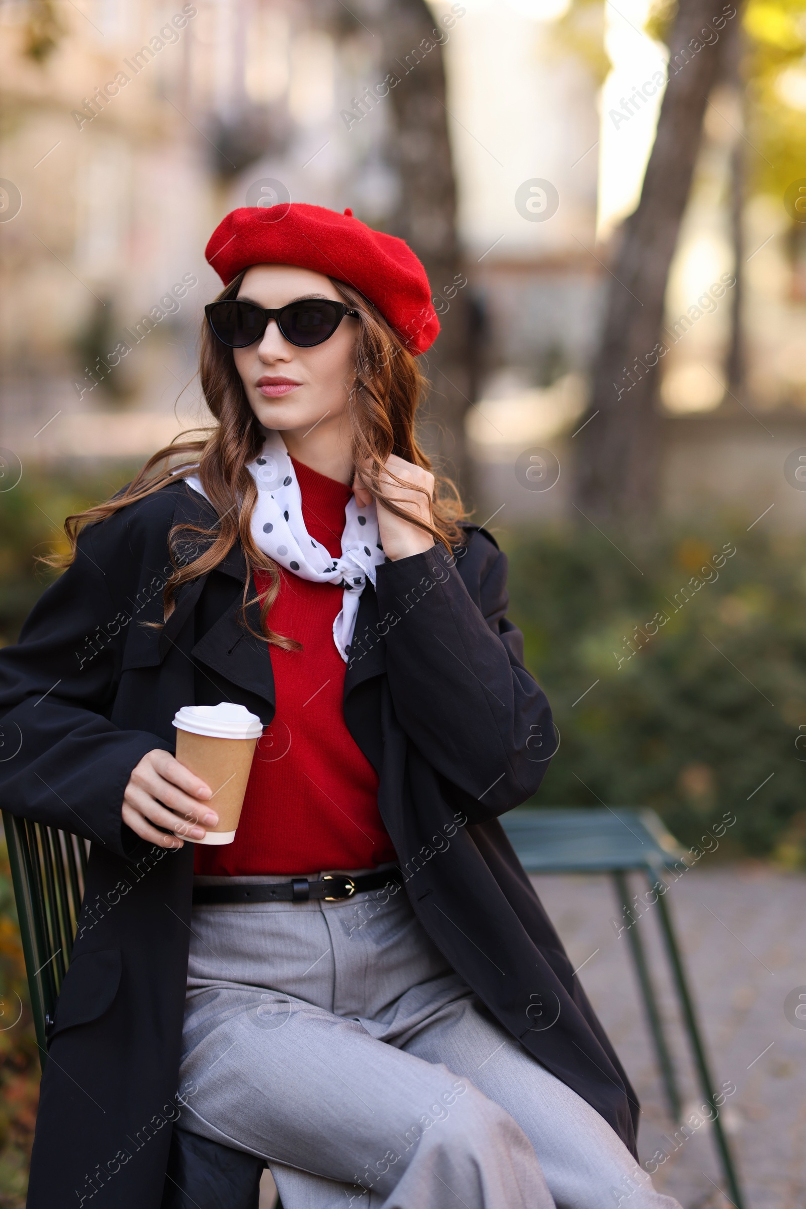 Photo of Stylish woman with cup of hot drink outdoors