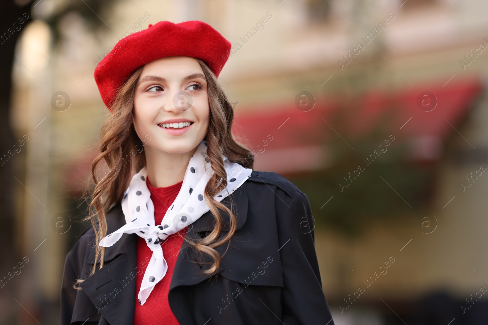 Photo of Stylish young woman with red beret on city street, space for text