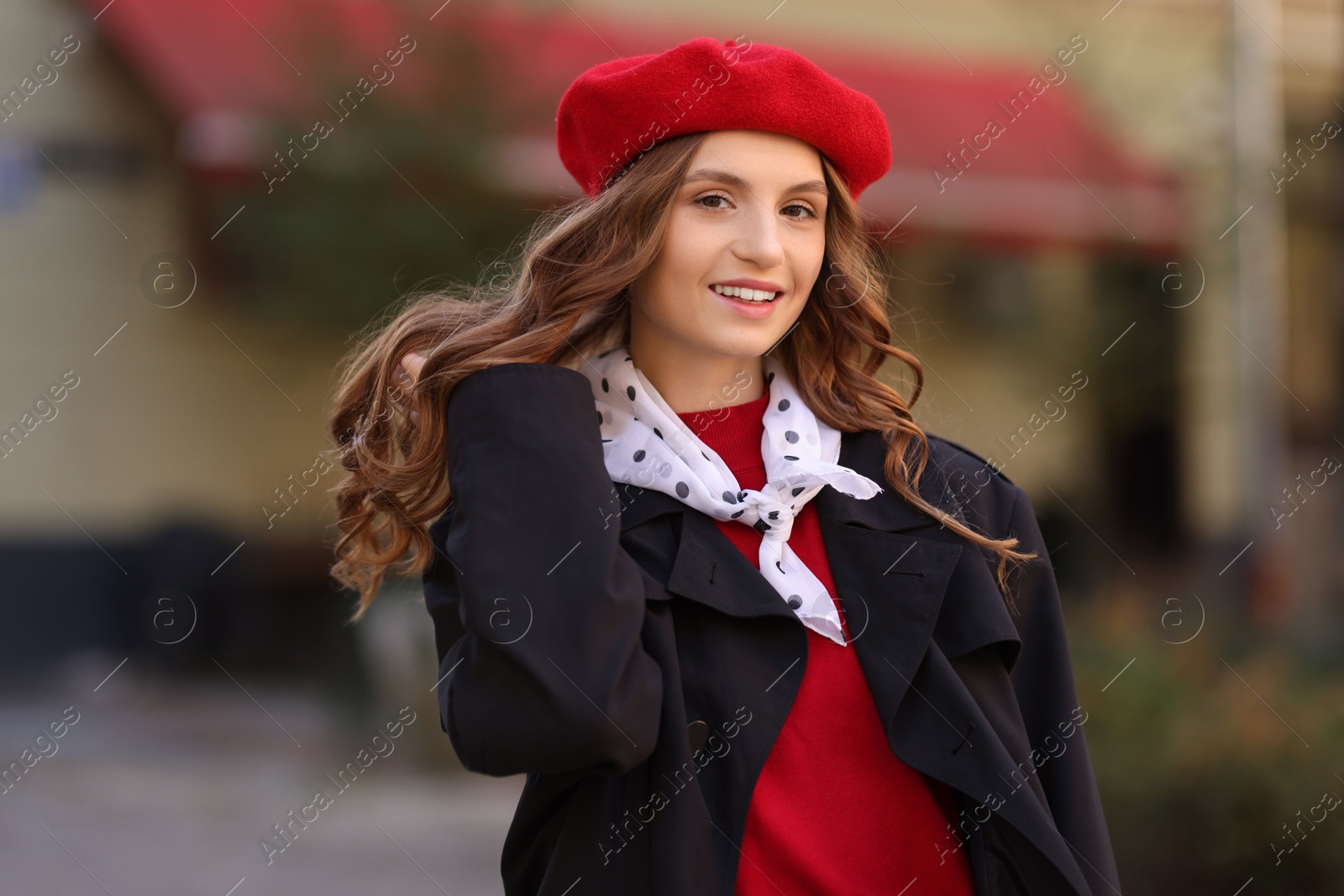 Photo of Stylish young woman with red beret on city street