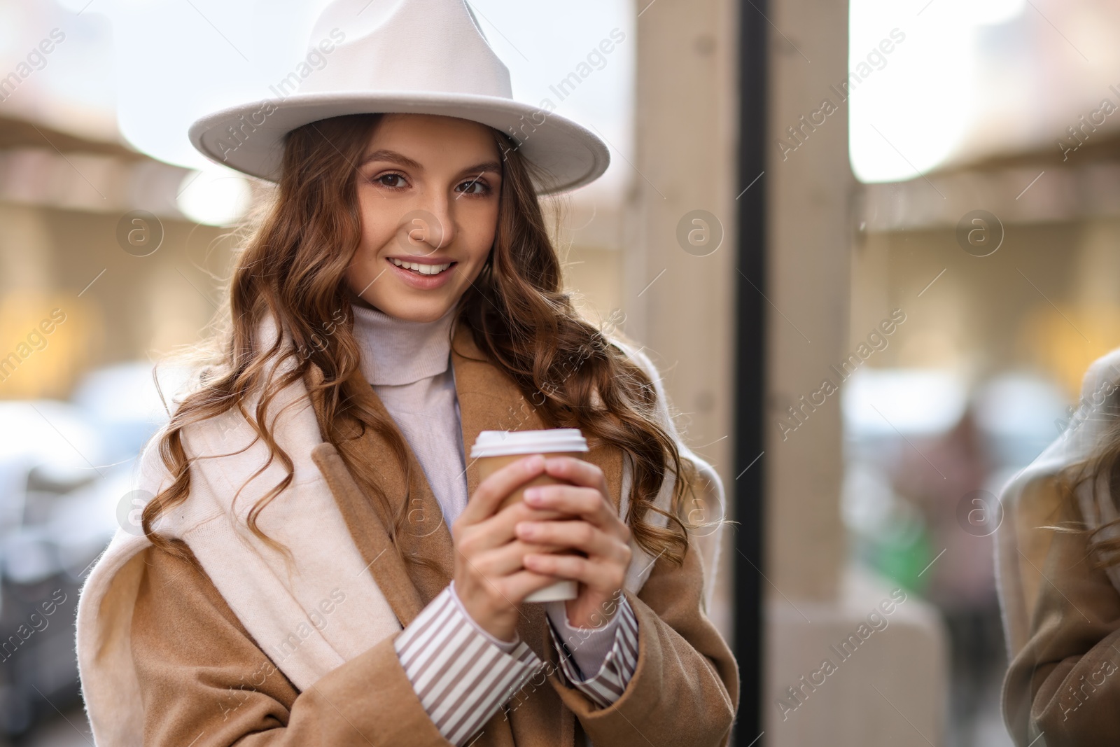 Photo of Charming young woman with hot drink near shop on city street, space for text