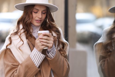 Photo of Charming young woman with hot drink near shop on city street, space for text