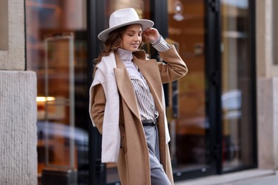 Charming young woman near shop on city street