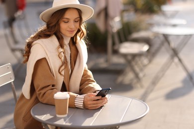 Photo of Stylish woman with smartphone in outdoor cafe, space for text. Autumn mood