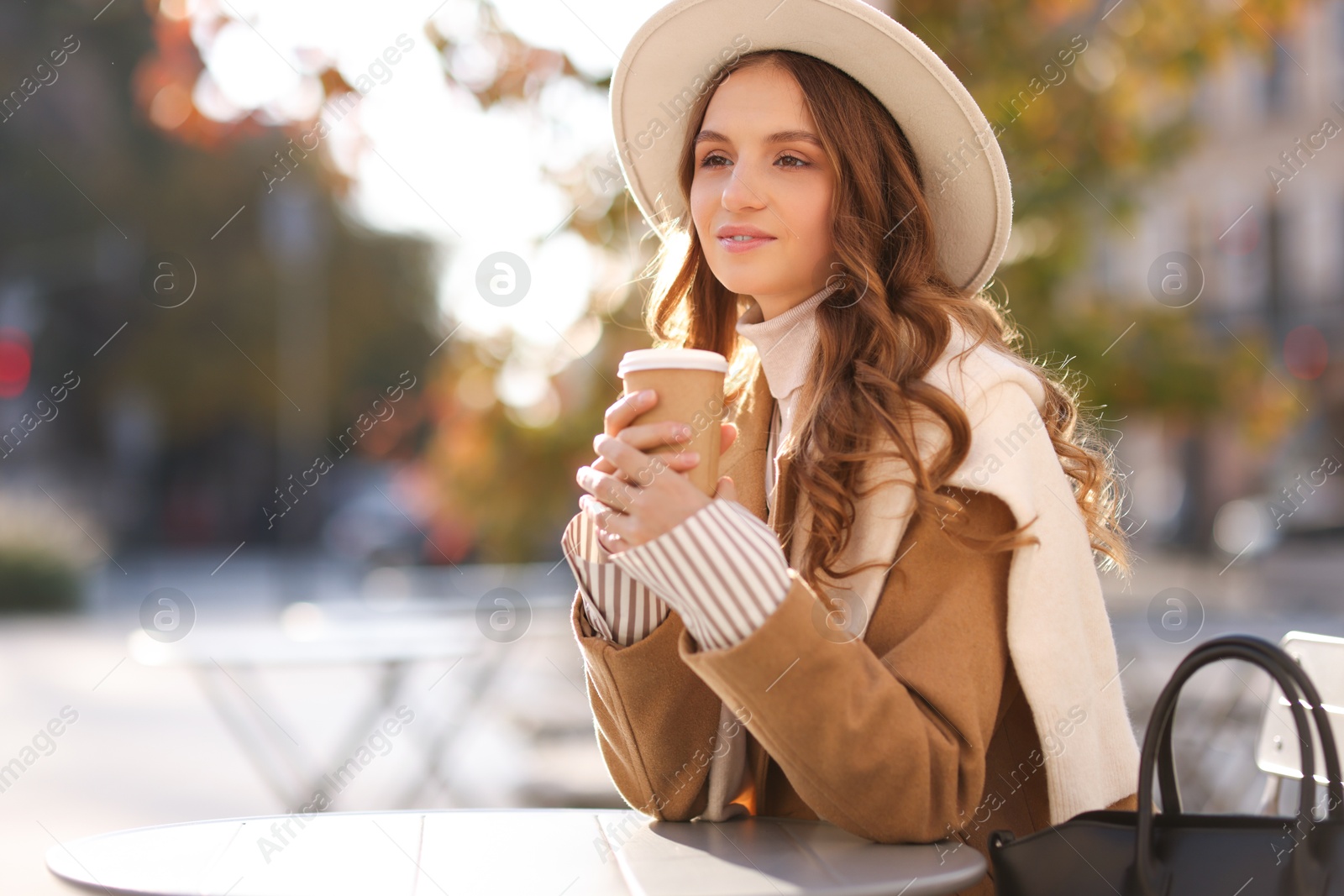 Photo of Stylish woman at table in outdoor cafe, space for text. Autumn mood