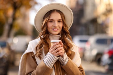 Photo of Stylish woman with cup of coffee outdoors. Autumn mood