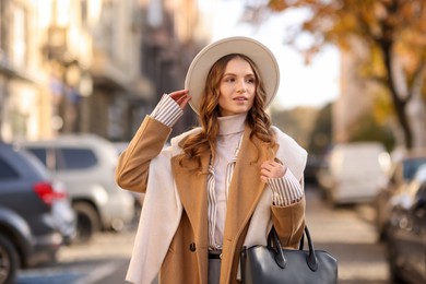 Photo of Young woman in beautiful outfit on city street. Autumn style