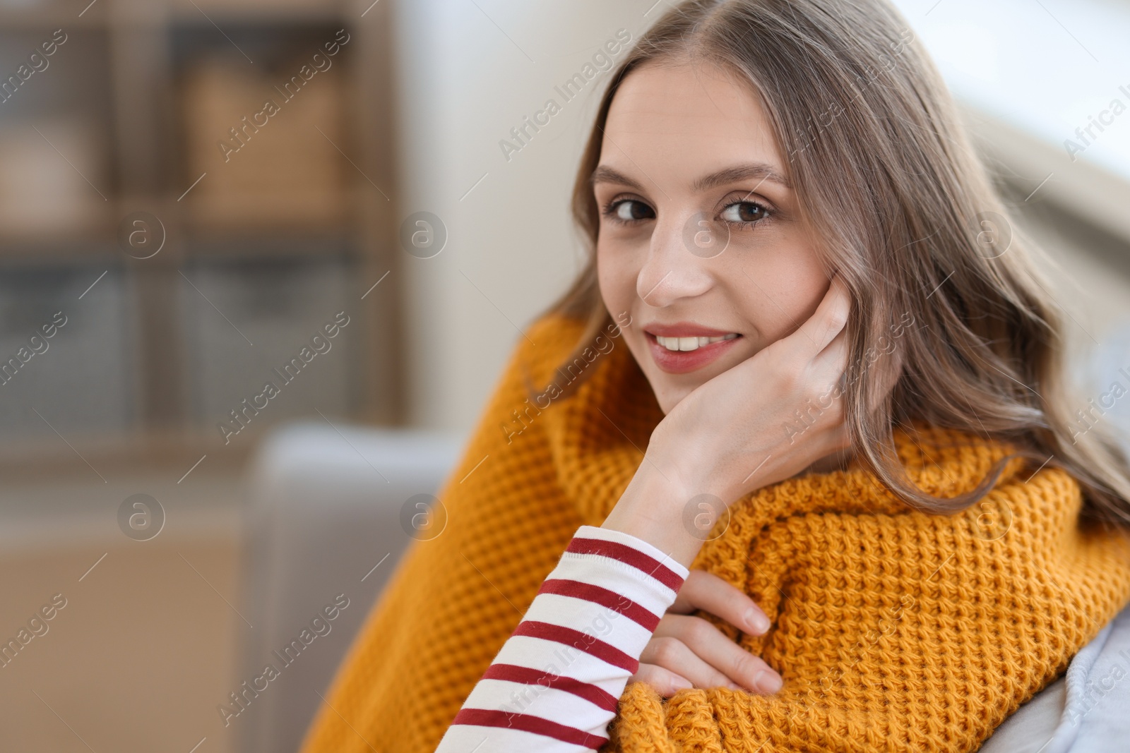 Photo of Charming young woman on sofa at home, space for text. Autumn atmosphere