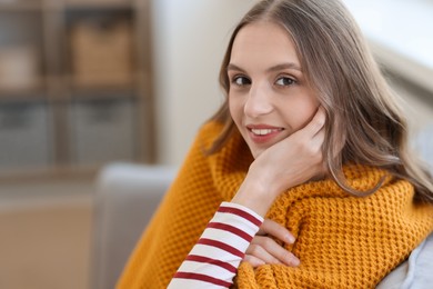 Photo of Charming young woman on sofa at home, space for text. Autumn atmosphere