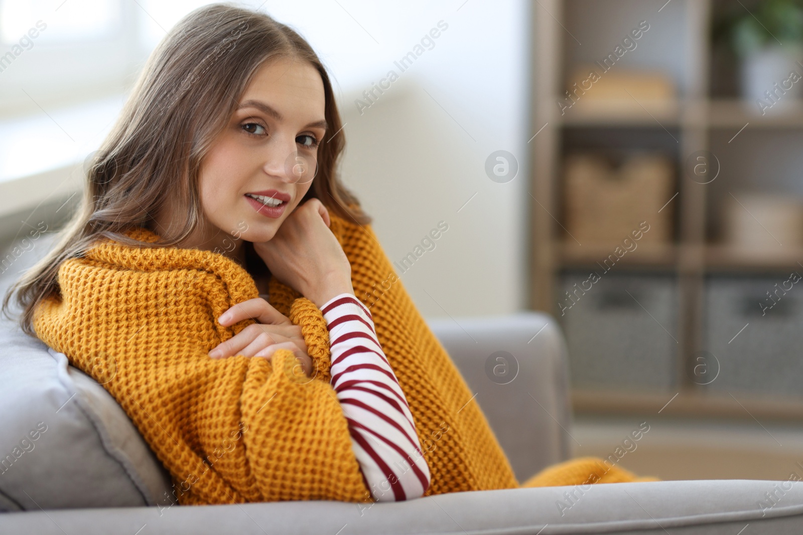 Photo of Charming young woman on sofa at home, space for text. Autumn atmosphere