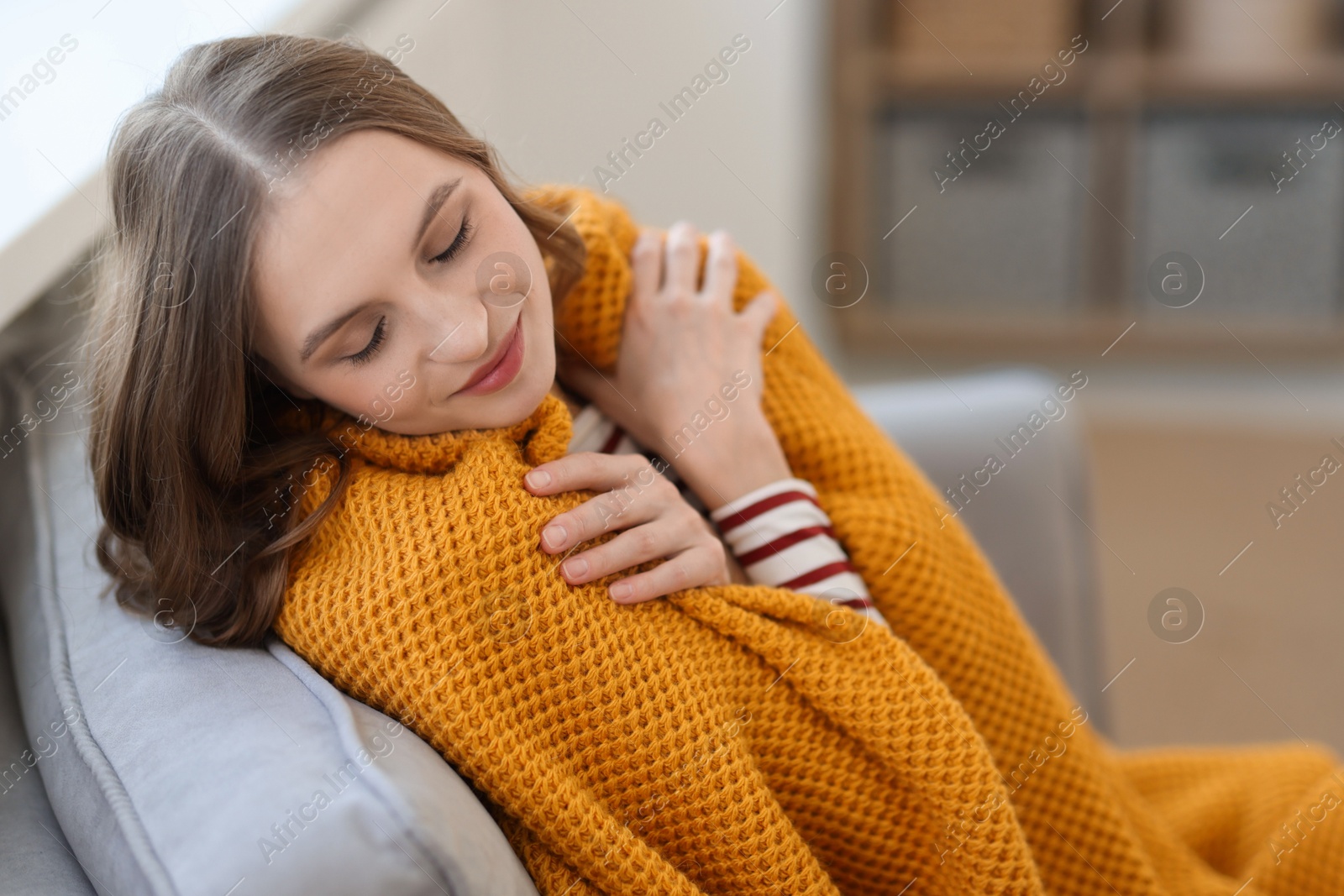 Photo of Charming young woman on sofa at home. Autumn atmosphere