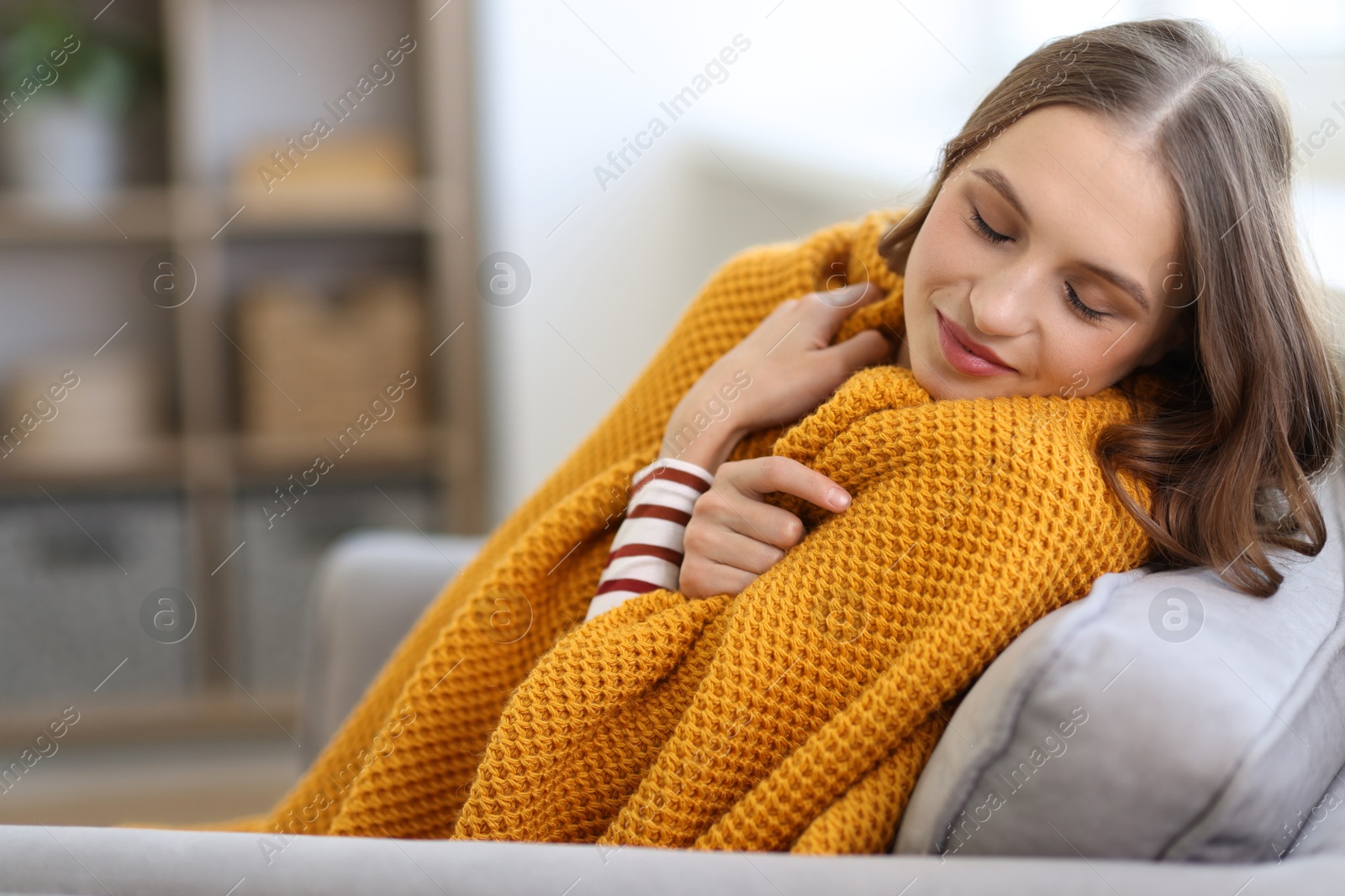 Photo of Charming young woman on sofa at home, space for text. Autumn atmosphere