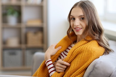 Photo of Charming young woman on sofa at home, space for text. Autumn atmosphere