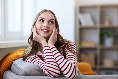 Photo of Charming young woman on sofa at home, space for text. Autumn atmosphere