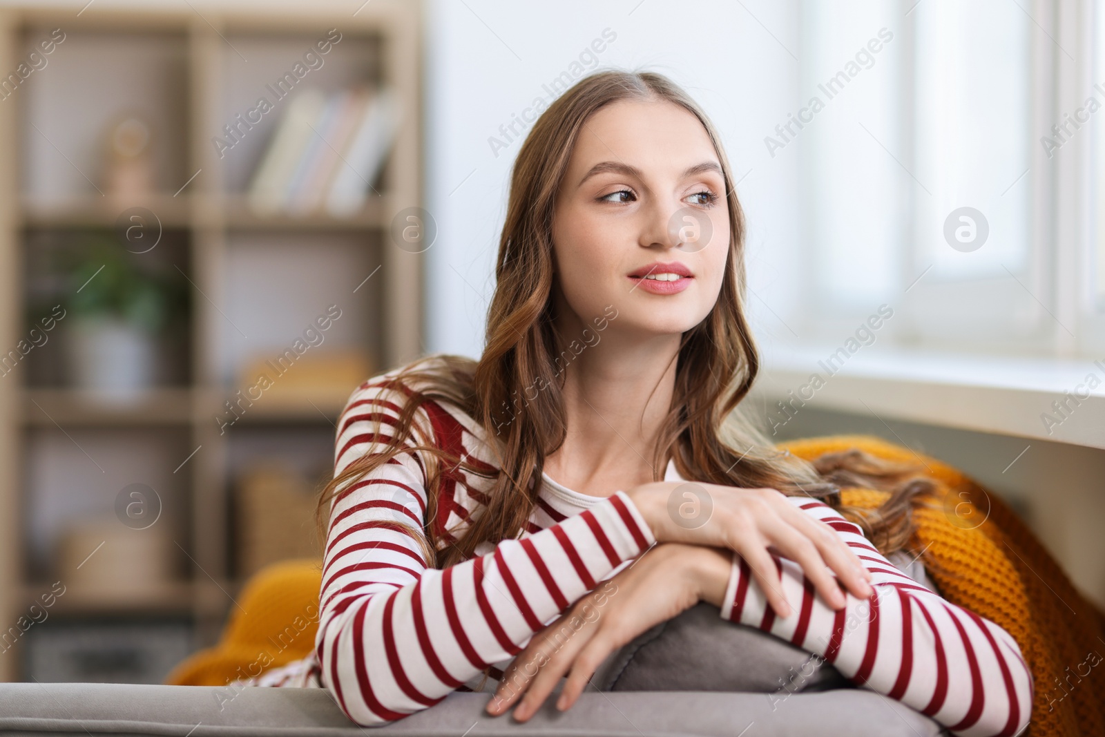 Photo of Charming young woman on sofa at home. Autumn atmosphere