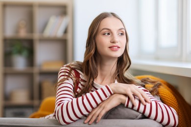 Charming young woman on sofa at home. Autumn atmosphere