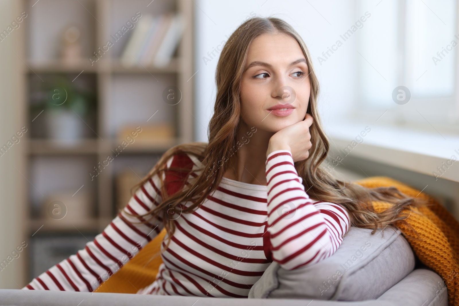 Photo of Charming young woman on sofa at home. Autumn atmosphere