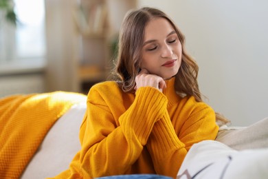 Photo of Charming young woman on sofa at home. Autumn atmosphere