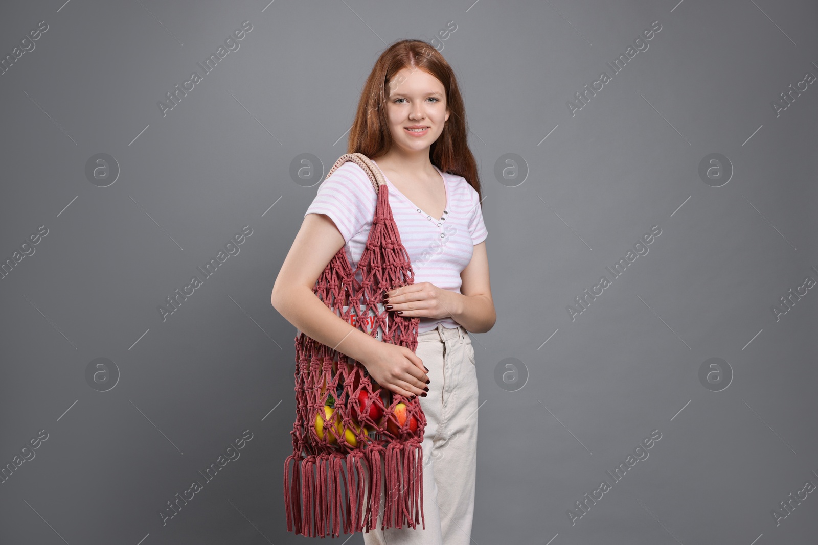 Photo of Teenage girl with handmade macrame bag on grey background