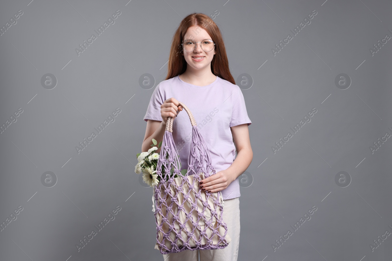 Photo of Teenage girl with handmade macrame bag on grey background