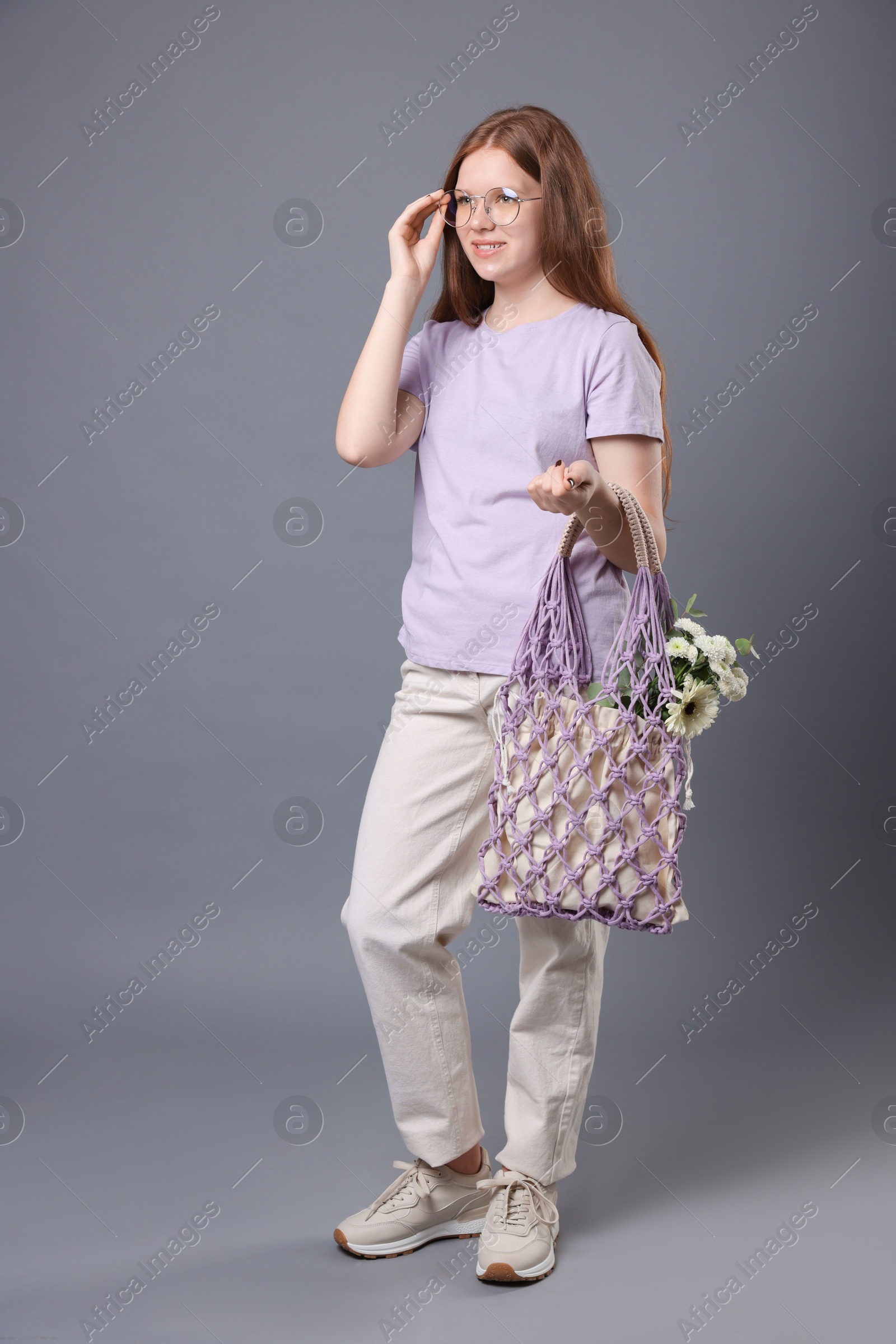 Photo of Teenage girl with handmade macrame bag on grey background