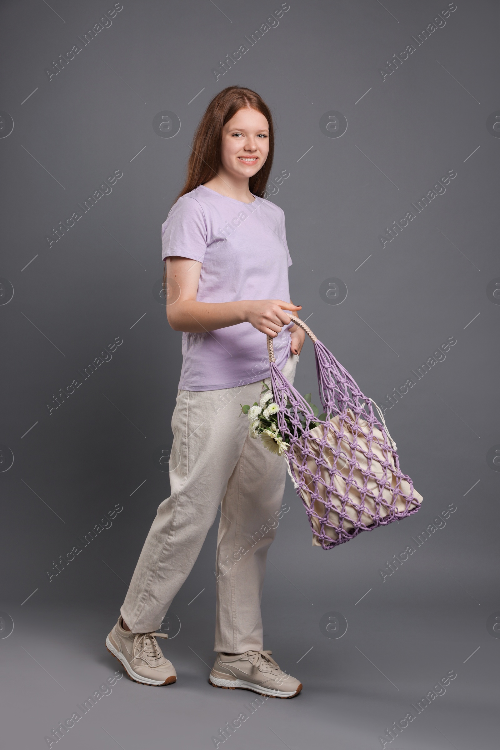 Photo of Teenage girl with handmade macrame bag on grey background