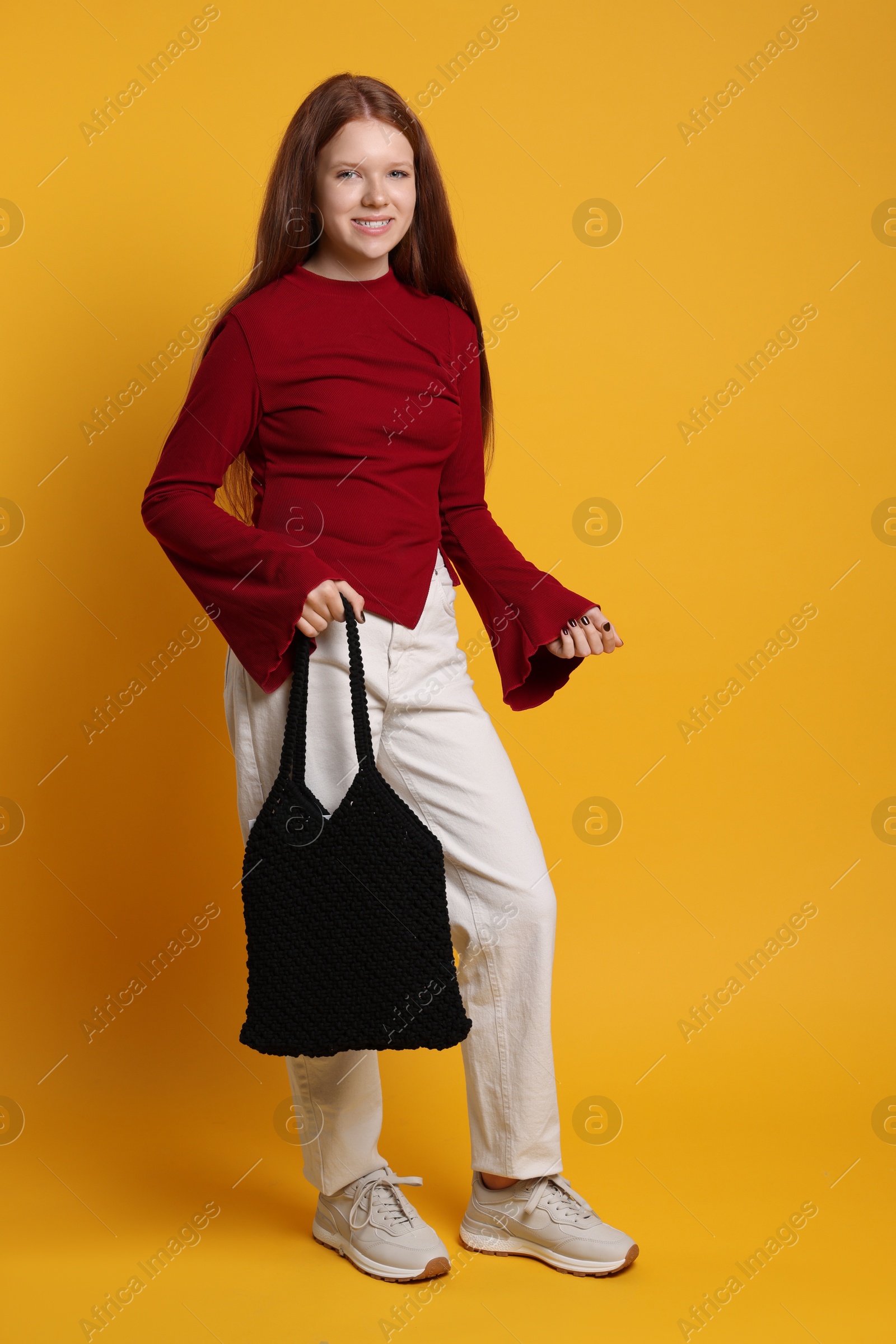 Photo of Teenage girl with handmade macrame bag on yellow background