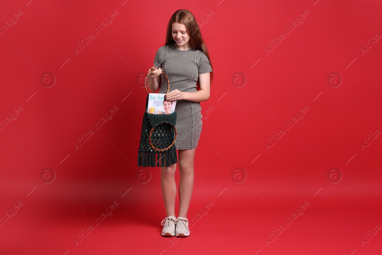 Photo of Teenage girl with handmade macrame bag on red background