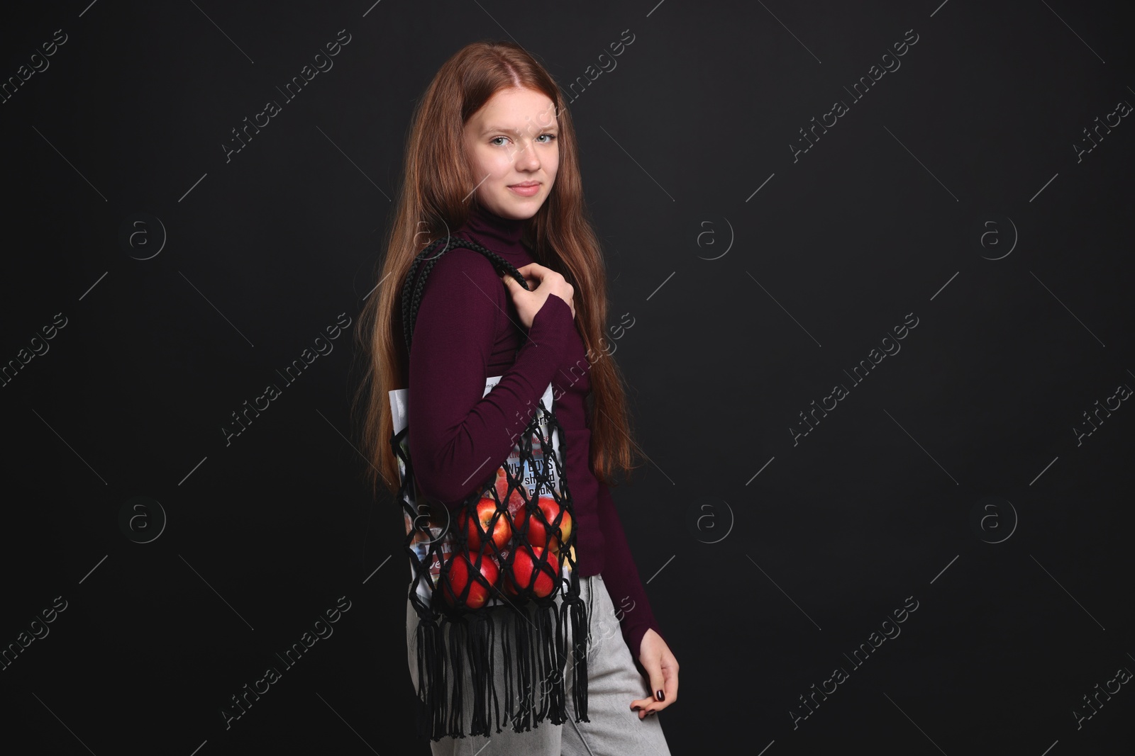 Photo of Teenage girl with handmade macrame bag on black background