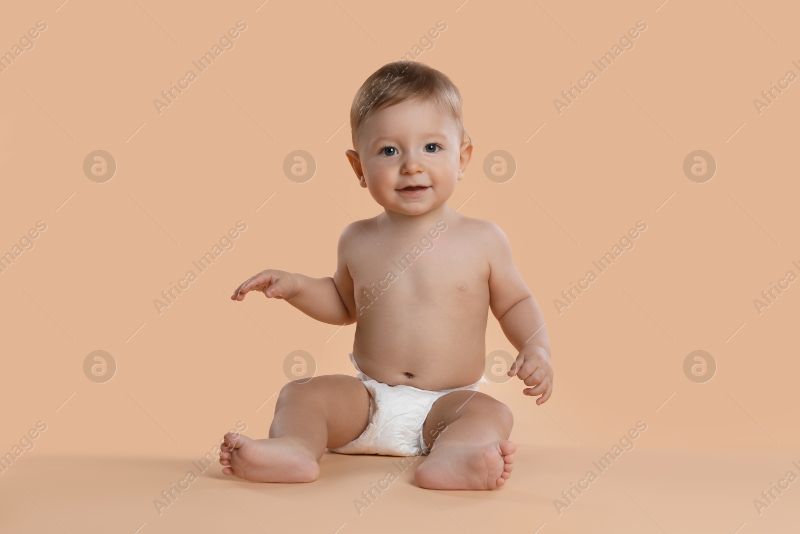 Photo of Cute little baby in diaper sitting on beige background