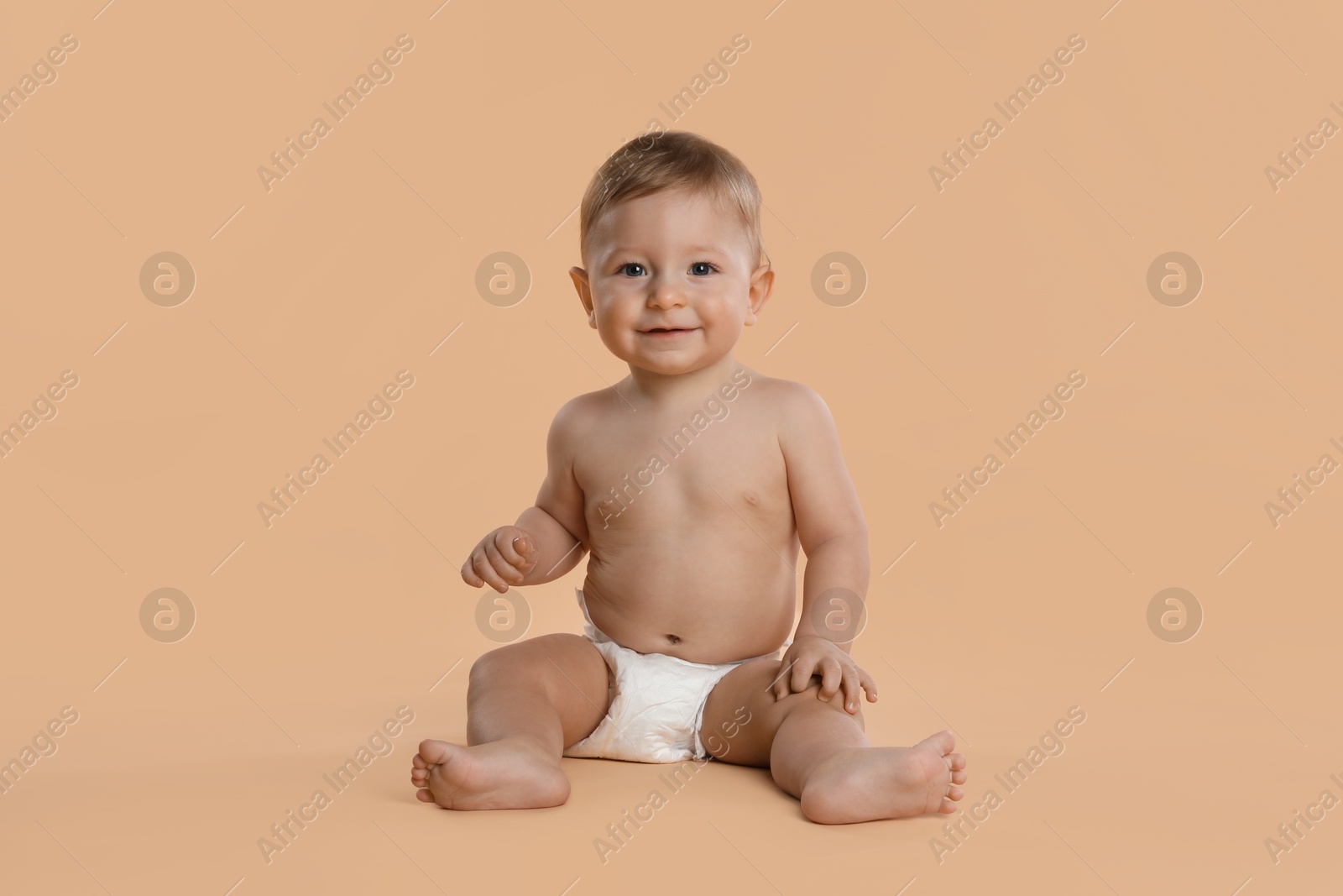 Photo of Cute little baby in diaper sitting on beige background