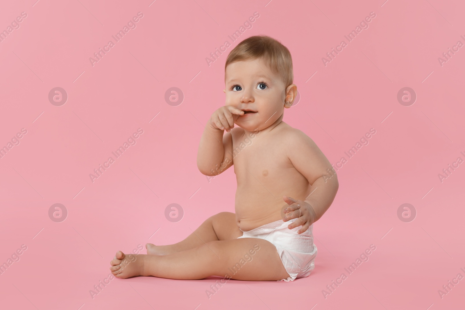 Photo of Cute little baby in diaper sitting on pink background