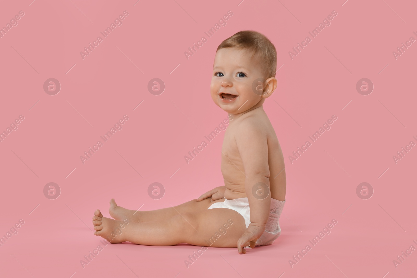 Photo of Cute little baby in diaper sitting on pink background