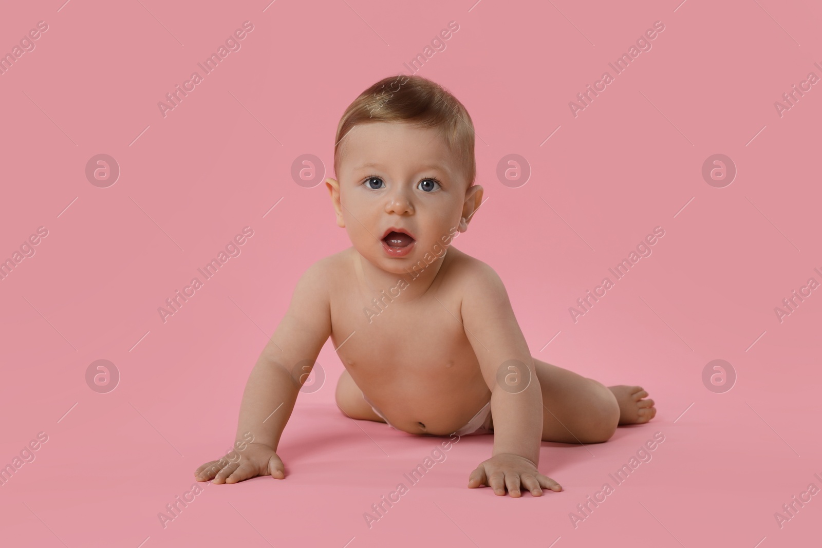 Photo of Cute little baby in diaper crawling on pink background