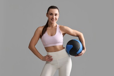 Photo of Woman in gym clothes doing exercise with medicine ball on grey background