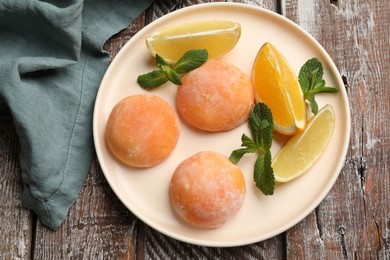 Photo of Plate with tasty mochi, cut orange, lemon and mint on wooden table, top view