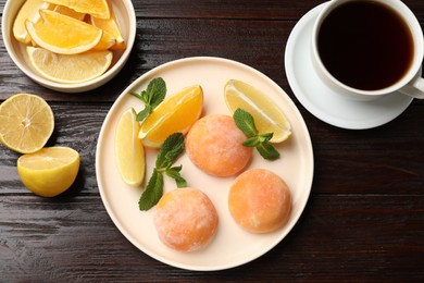 Photo of Tasty mochi, cut orange, lemon and mint served with tea on wooden table, flat lay